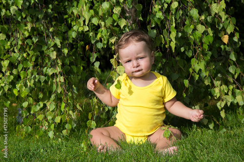 Little boy sitting under the tree in sunny day