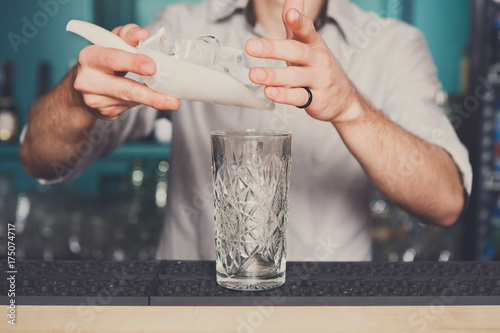 Bartender hands pouring ice for cocktail