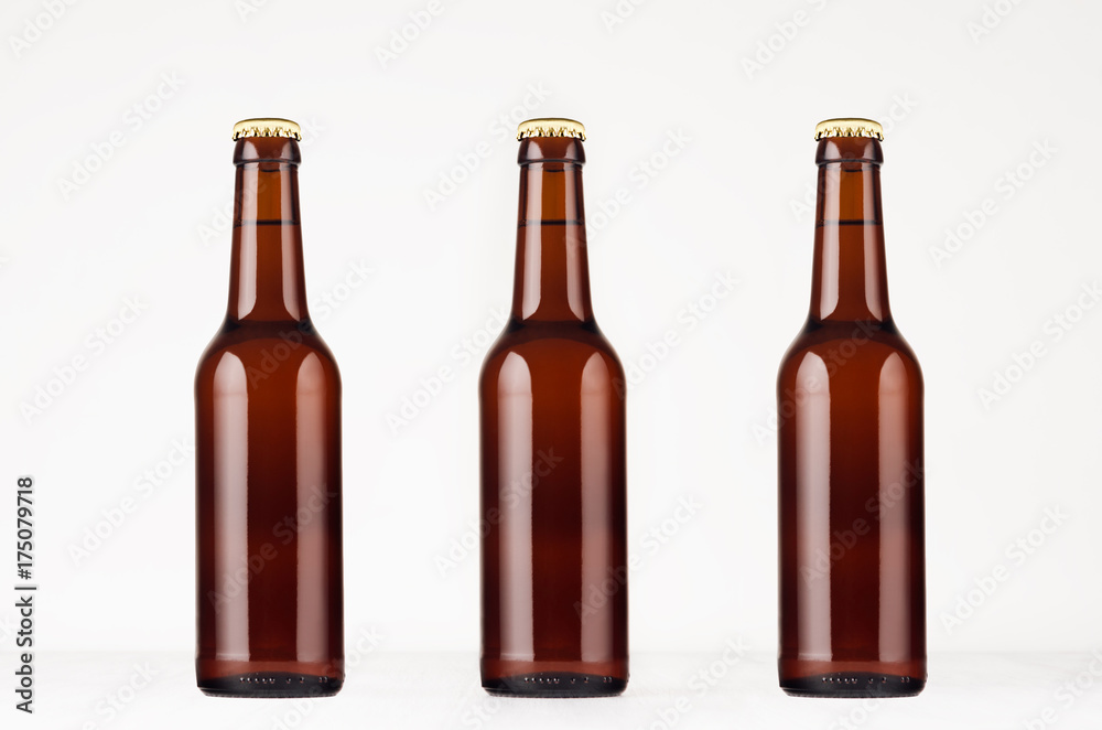 Three brown longneck beer bottle 330ml mock up. Template on white wood table. Three brown longneck beer bottle 330ml mock up. Template on white wood table.