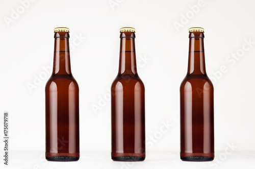 Three brown longneck beer bottle 330ml mock up. Template on white wood table.