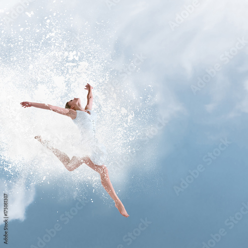 Beautiful ballet dancer jumping with cloud of powder