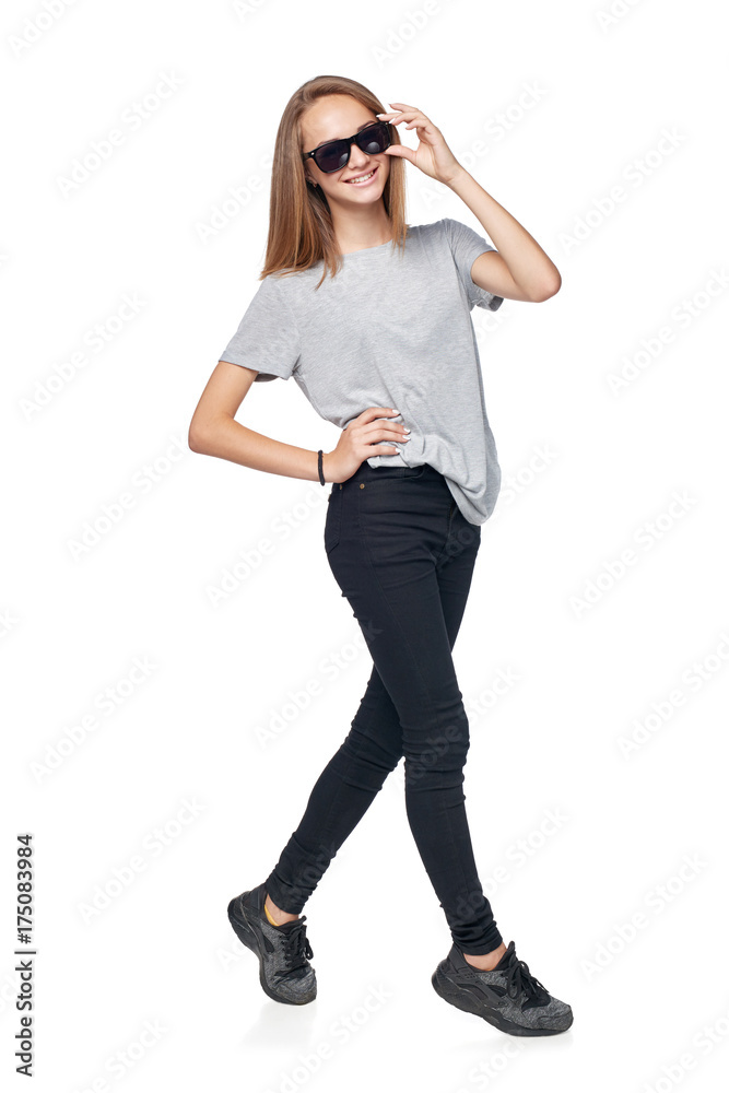 Teen girl in sunglasses in full length standing casually smiling at camera, isolated on white background Teen girl in sunglasses in full length standing casually smiling at camera, isolated on white background