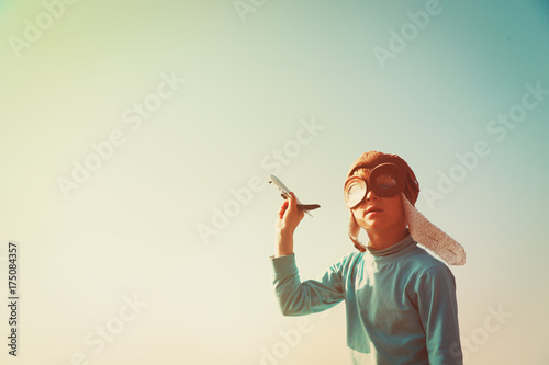 little boy with helmet and glasses play with toy plane on sky