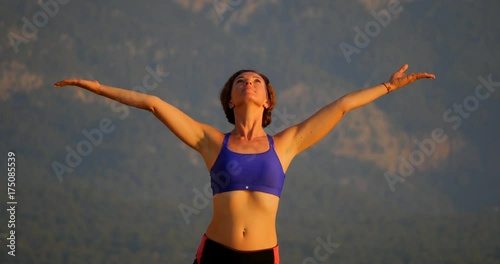 Front view portrait of beautiful young woman wearing sport topic salutating the sun photo