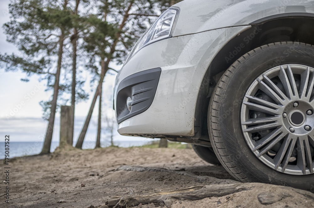 The car stands on the sandy shore against the backdrop of the lake and pine trees, spring day. The car stands on the sandy shore against the backdrop of the lake and pine trees, spring day.