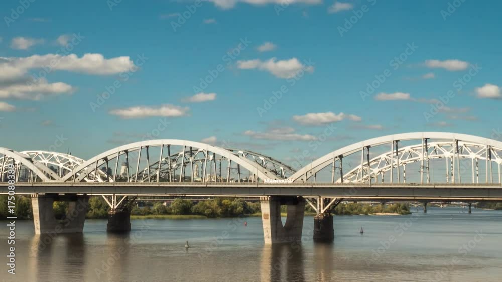 The movement of clouds over the bridge along which cars and trains are moving, a river flows under the bridge, and early autumn has come. Panorama 4k proress 444 The movement of clouds over the bridge along which cars and trains are moving, a river flows under the bridge, and early autumn has come. Panorama 4k proress 444