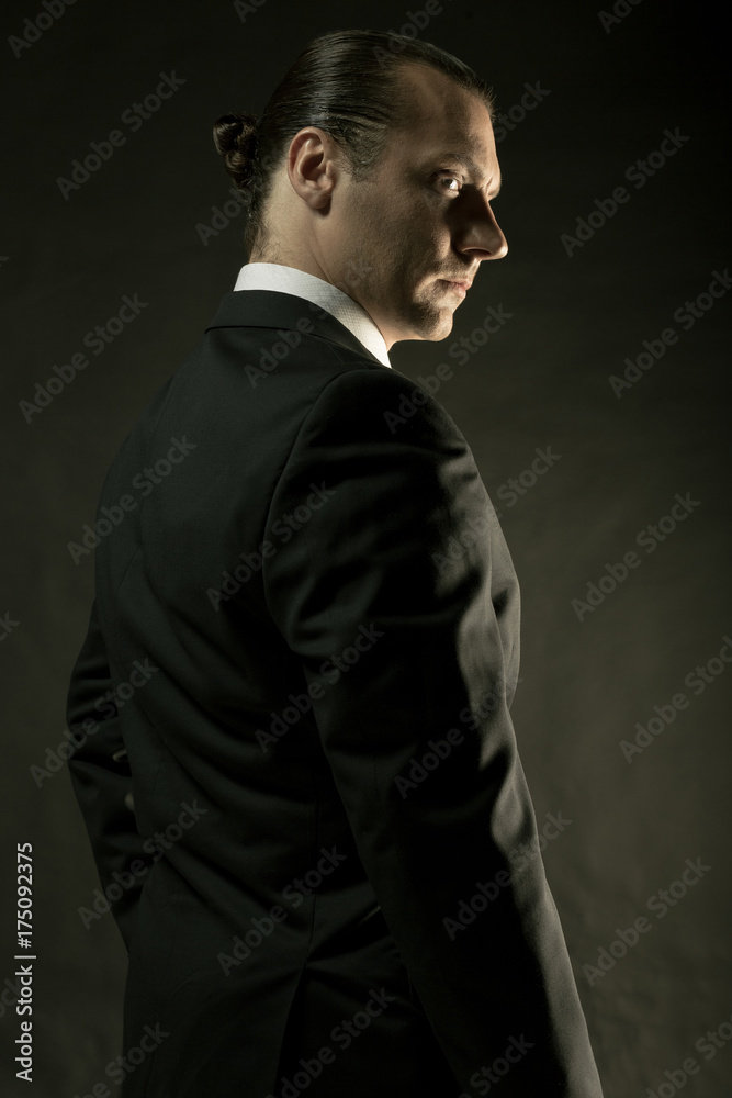 The attractive man in black suit on dark background The attractive man in black suit on dark background