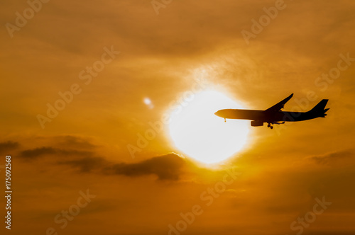 silhouette airplane preparing for landing with sunset.