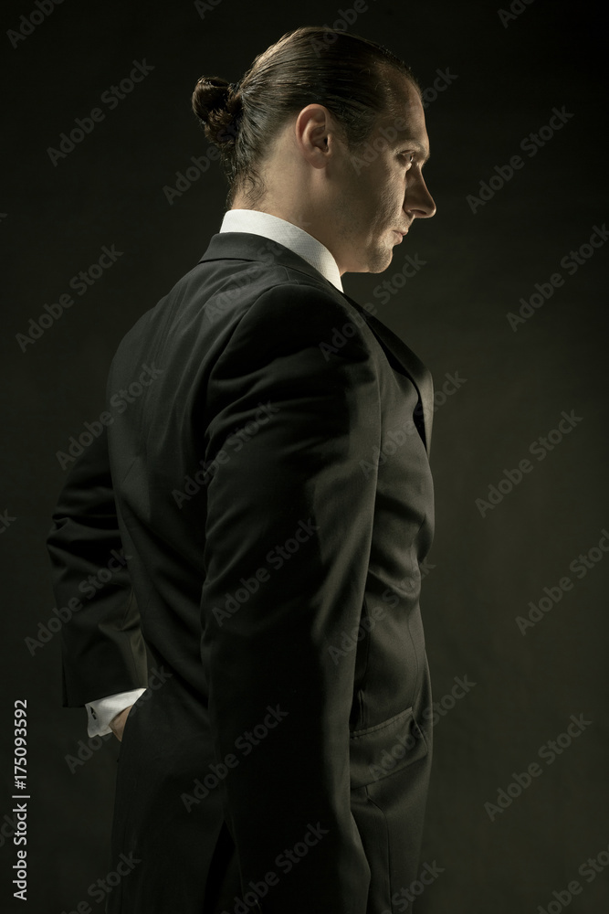 The attractive man in black suit on dark background The attractive man in black suit on dark background
