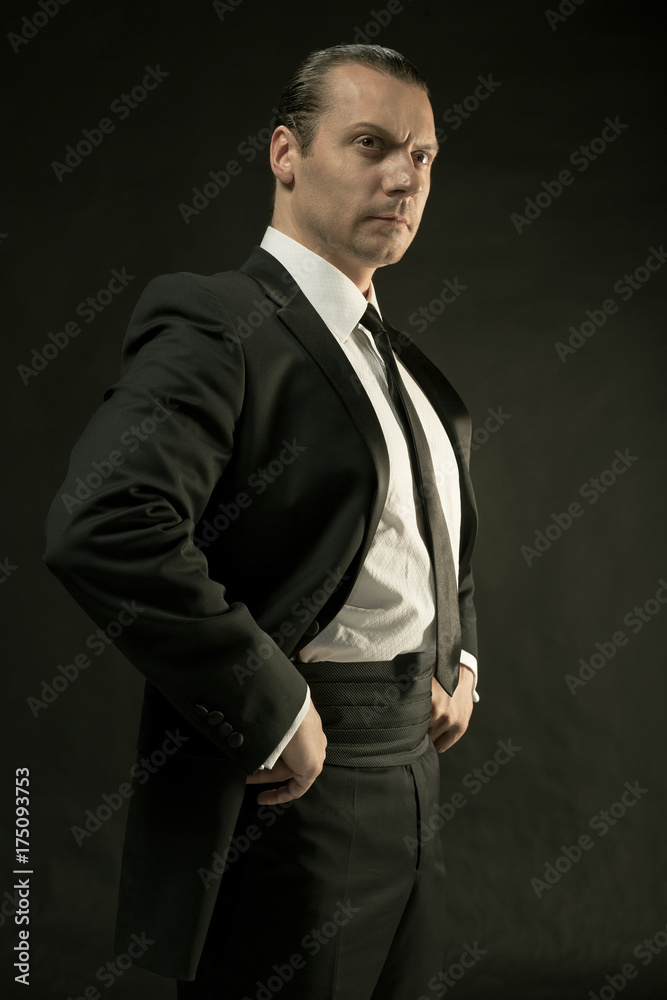 The attractive man in black suit on dark background
