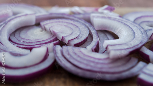 Food preparation, cooking concept: sliced fresh red onions on rustic wooden background photo