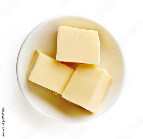 Butter pieces in bowl isolated on white background, top view