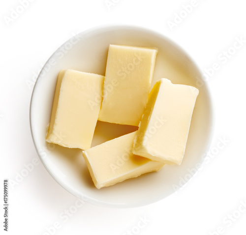 Butter pieces in bowl isolated on white background, top view