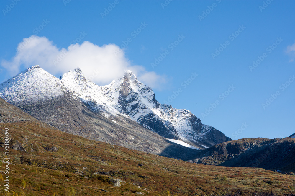 Mountain scenery with snow on the high peaks against blue sky background