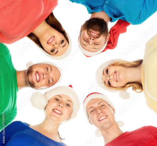 Group of smiling friends in Christmas hats embracing together. Isolated white background. New Year  Xmas  X-mas celebrating concept.