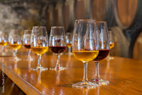 glasses of red and white port wine with barrels in background, wine degustation