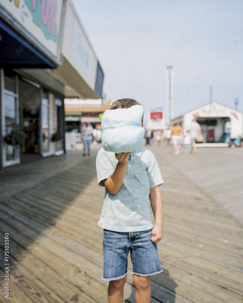 Young boy hiding behind his cotton candy on a Jersey Shore boardwalk Young boy hiding behind his cotton candy on a Jersey Shore boardwalk