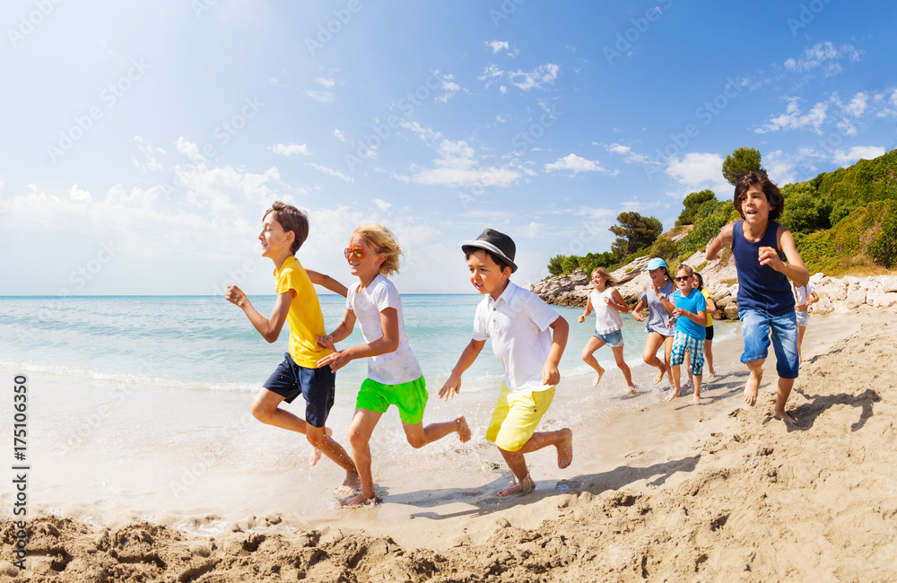 Large group of kids run on a beach along the sea Large group of kids run on a beach along the sea