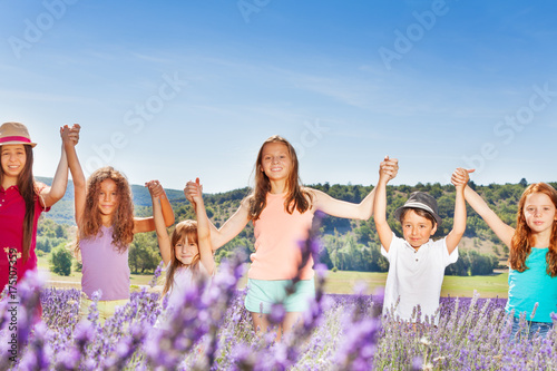 Happy kids holding hands up in lavender field