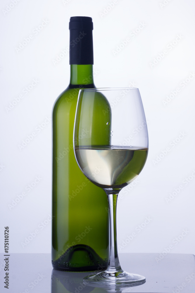 High glass with still white wine and green wine bottle High glass with still white wine and green wine bottle