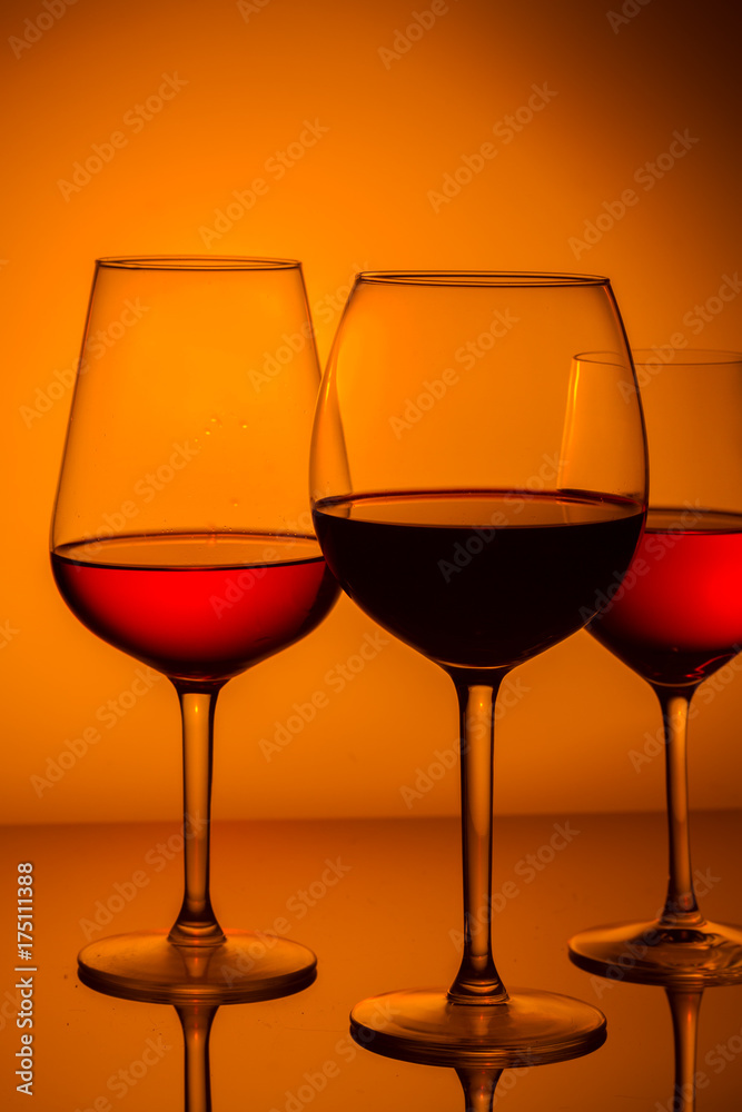 Set of wine glasses with red and rose wine on orange background Set of wine glasses with red and rose wine on orange background