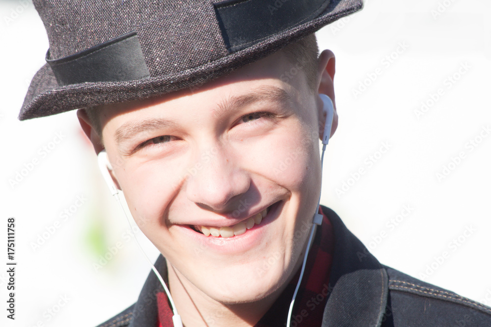 Young man wearing hat walking on the street and chatting by his phone while listening music with headphones Young man wearing hat walking on the street and chatting by his phone while listening music with headphones