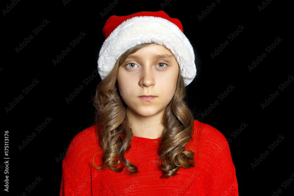 A sad girl in a red sweater and a Santa Claus hat looks at the viewer. A sad girl in a red sweater and a Santa Claus hat looks at the viewer.