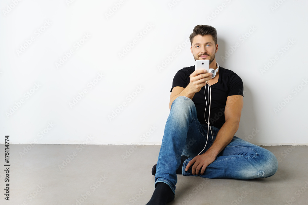 Fototapeta premium mann sitzt auf dem fußboden und hört musik