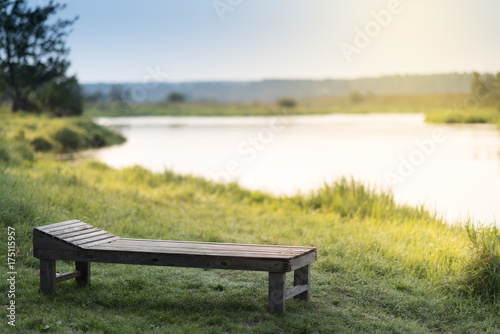 Vintage wooden Sun bed on a grass at the sunny river bank photo