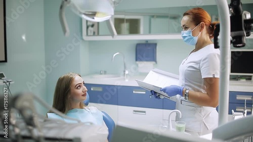 A woman stomotologist talking to a girl with a patient in a dental office photo