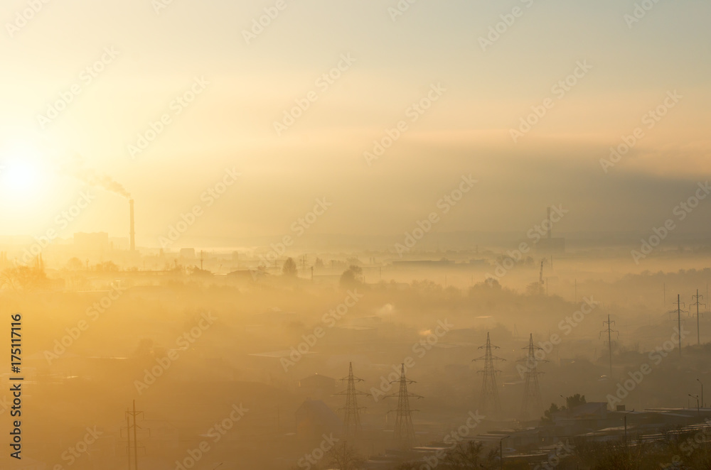 The industrial part of a small city in the fog at dawn.