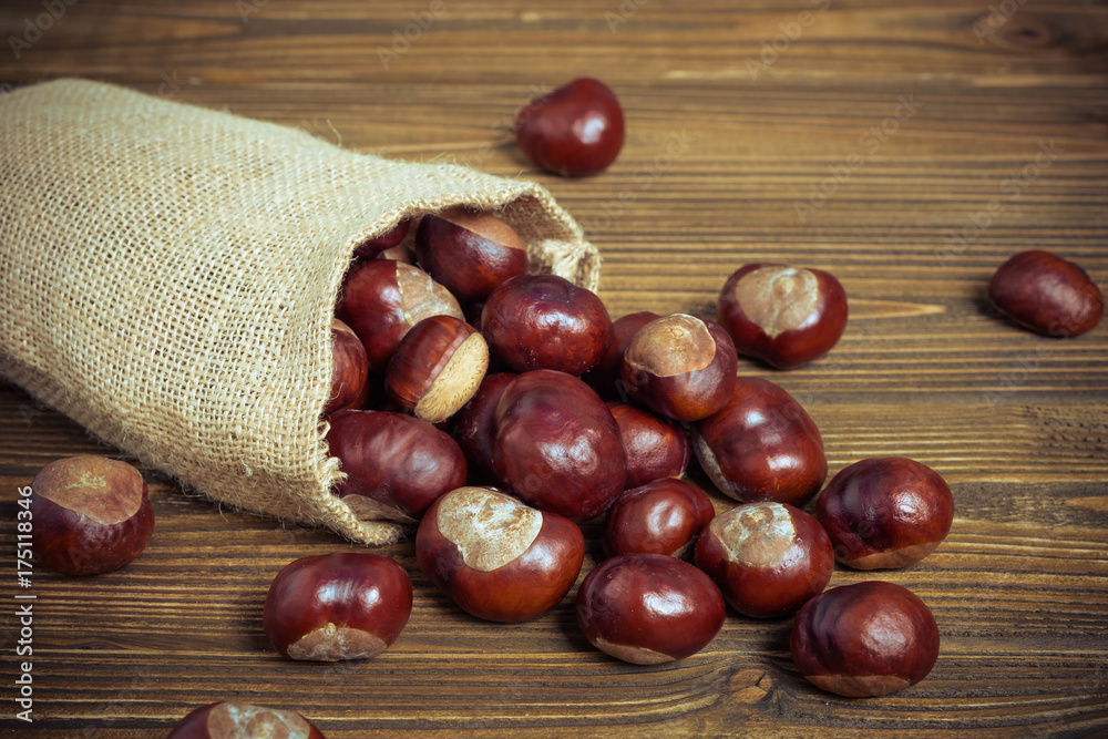 Chestnuts in jute sack on wooden background Chestnuts in jute sack on wooden background