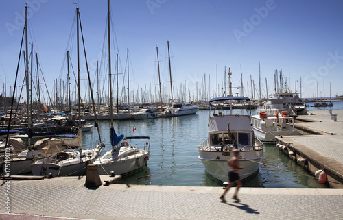 Man runs by Palma de Mallorca marina. Many yachts parked. It's a resort city and capital of the Spanish island of Majorca in the western Mediterranean.