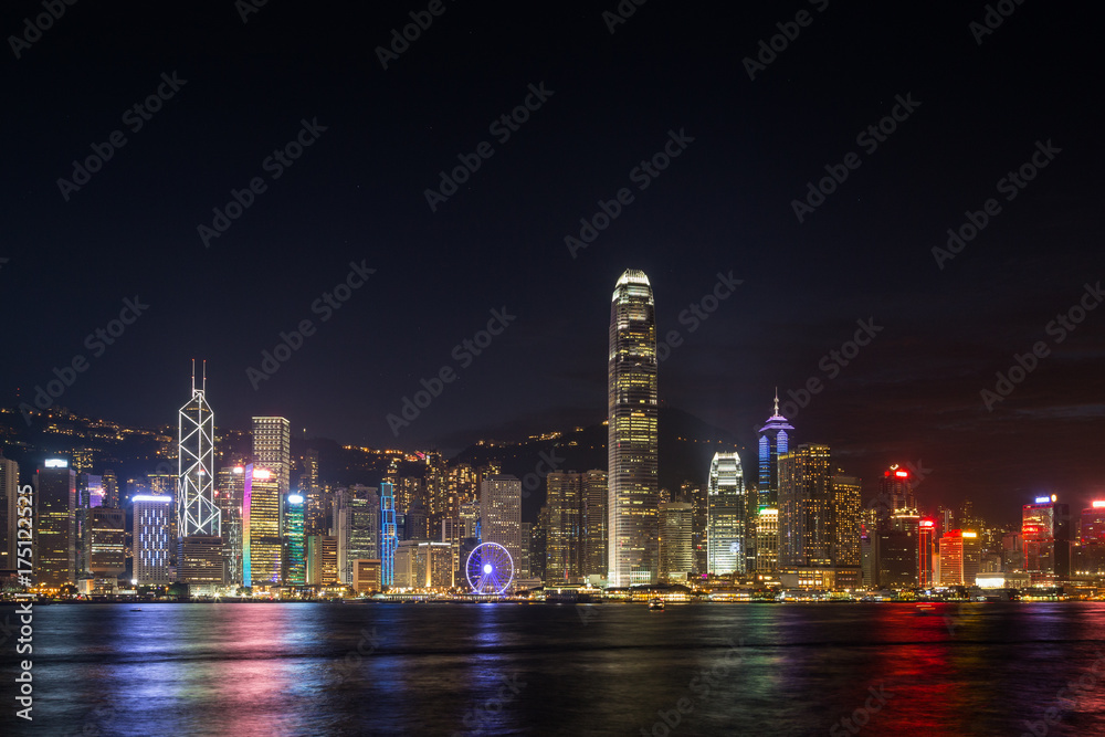 Hong Kong Island's skyline over Victoria Harbour with lit modern skyscrapers at night in Hong Kong, China. Viewed from Tsim Sha Tsui, Kowloon. Copy space.