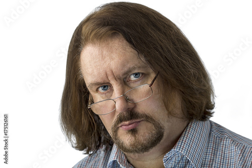A long-haired serious man with a beard looks at you. photo