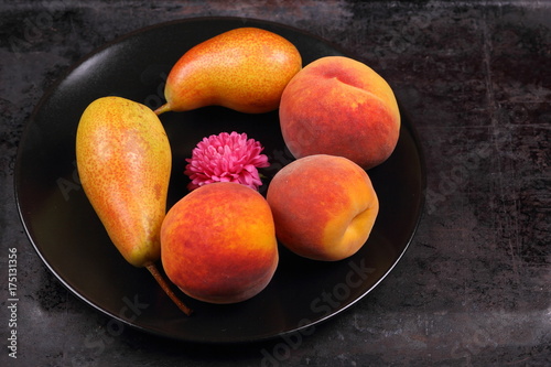 Pears and peaches on a black plate in retro style for a designer on a metal old background