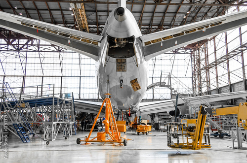 Large passenger aircraft on service in an aviation hangar rear view of the tail, on the auxiliary power unit. photo