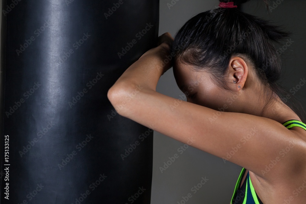 Exhausted female boxer leaning on punching bag Exhausted female boxer leaning on punching bag
