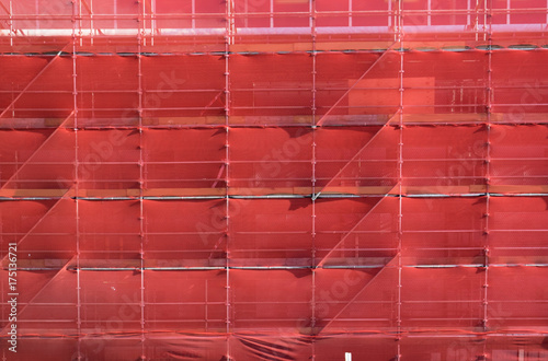 scaffolding on a building construction site covered with red safety netting