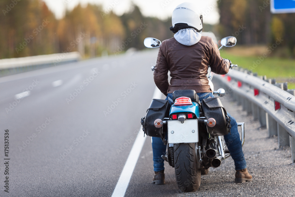 Rear view at woman on a motorcycle resting on the roadside of a country ...