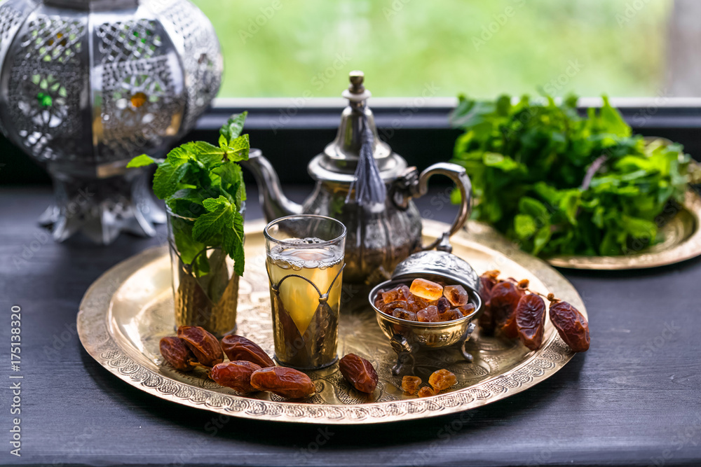 Moroccan tea with mint and sugar in a glasses on a copper plate with kettle Moroccan tea with mint and sugar in a glasses on a copper plate with kettle