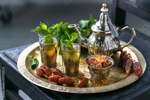 Moroccan mn tea in traditional glasses with mint, dates and sugar