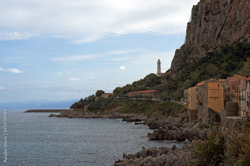 Sea shore of Cefalu with lighthouse on the mountain side, Sicily, Italy