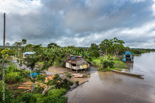Wide view of Amazon village with shacks and large blue boat