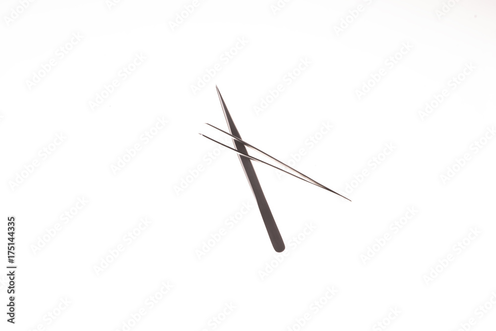 two crossed tweezers for eyelash extension on the white background two crossed tweezers for eyelash extension on the white background