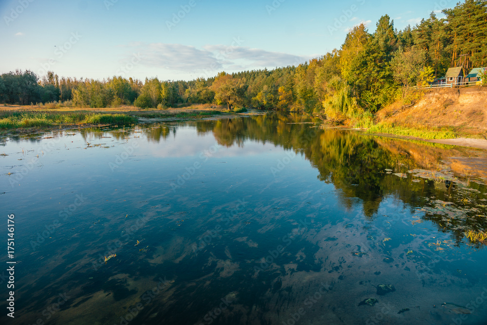 Fototapeta premium Nature of Europe. River bank with trees in autumn sunset.