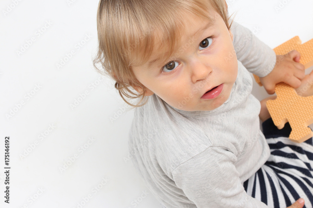 baby playing with a puzzle and looking towards the camera baby playing with a puzzle and looking towards the camera