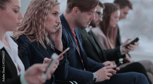 Businesspeople Using Technology In Busy Lobby Area Of Office