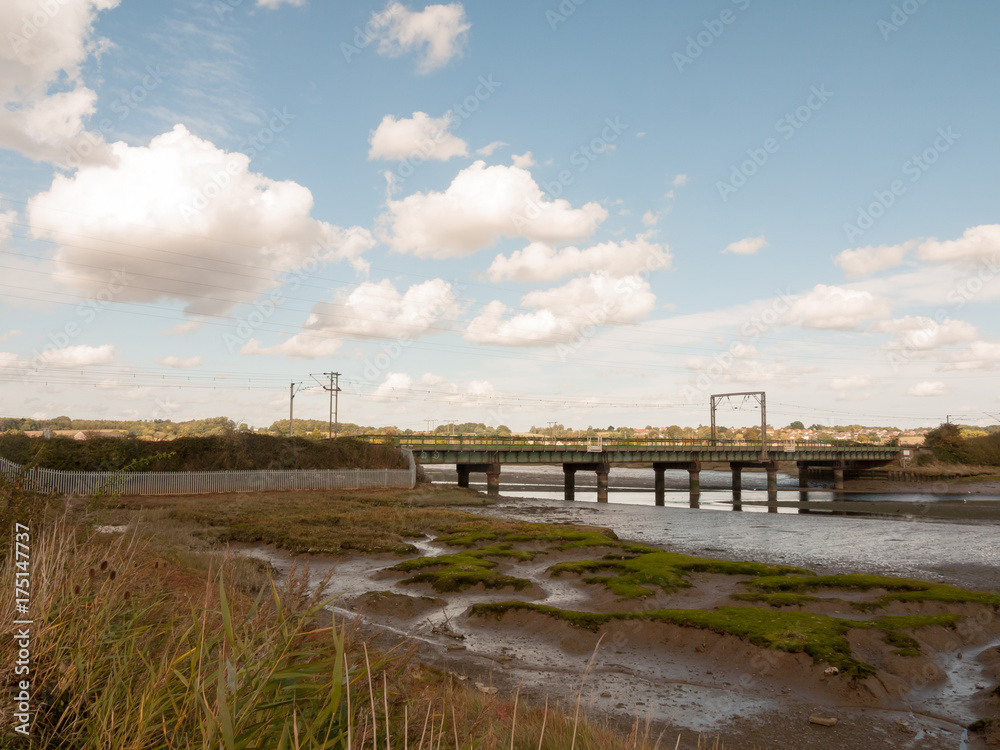 old unused bridge in the distance above estuary stream countryside