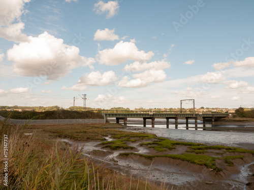 old unused bridge in the distance above estuary stream countryside